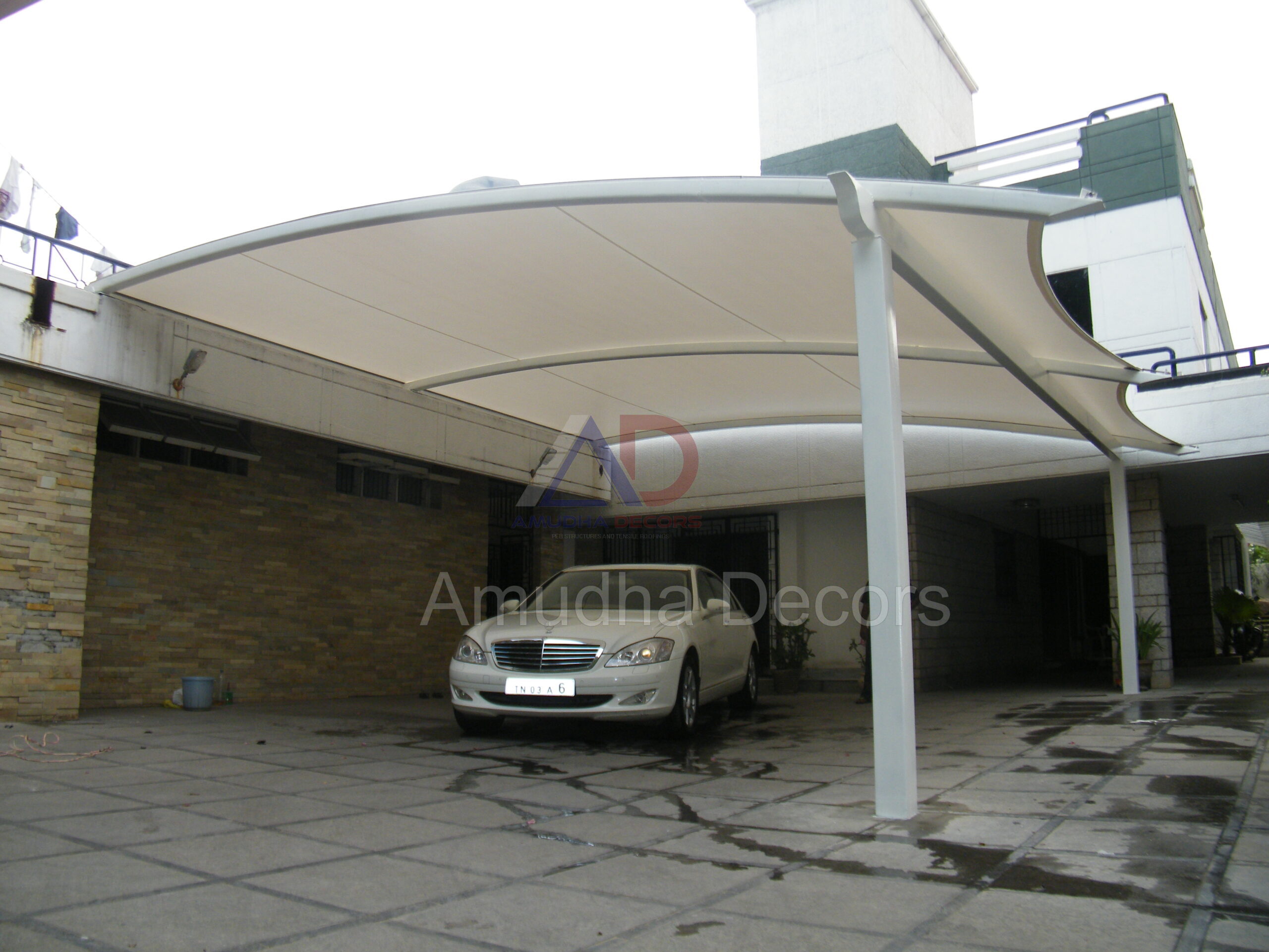 White tensile membrane car parking canopy installed at a residential building by Arasuvelroofings