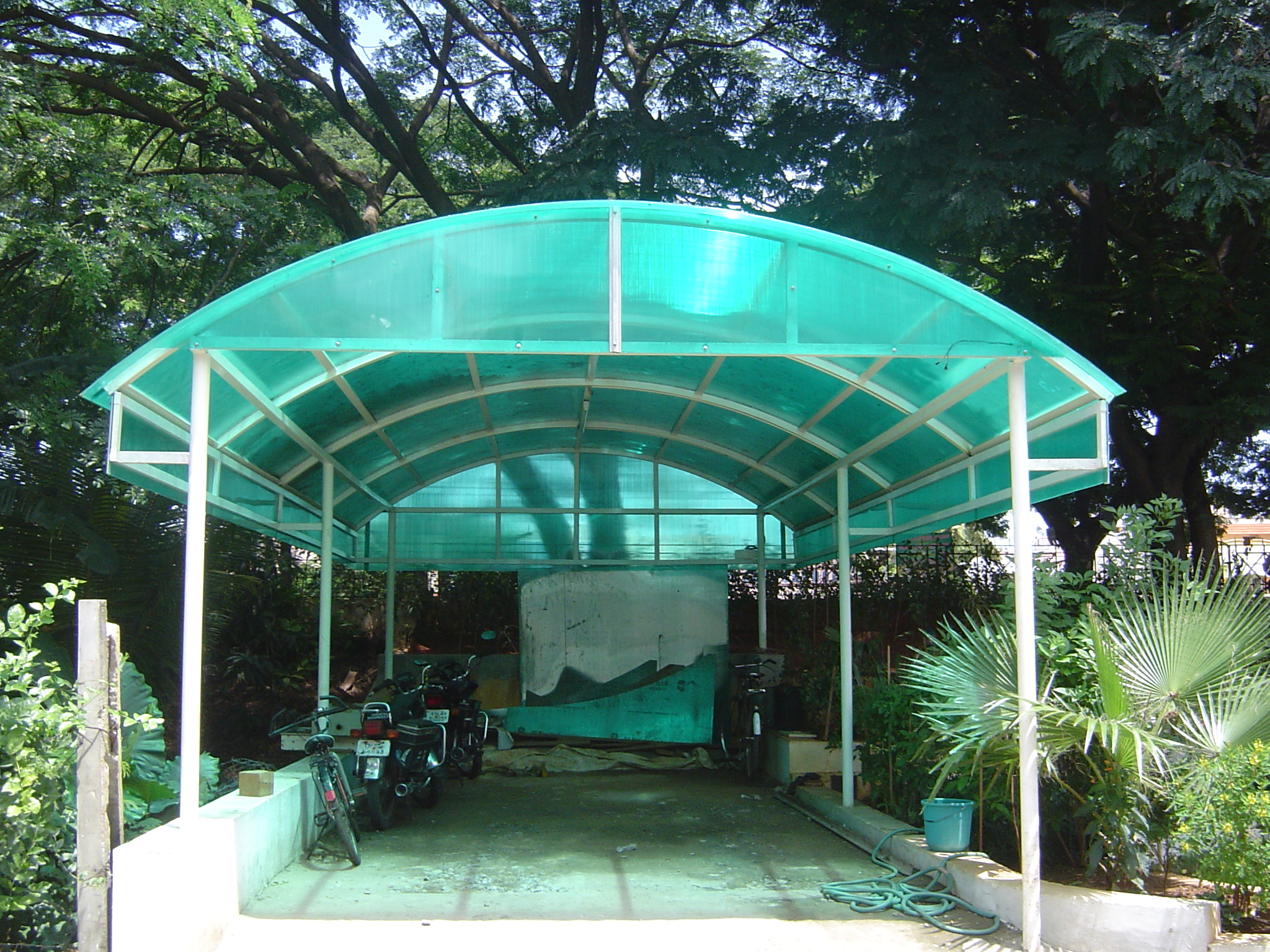 Green polycarbonate sheet car parking canopy installed by Arasuvel Roofings
